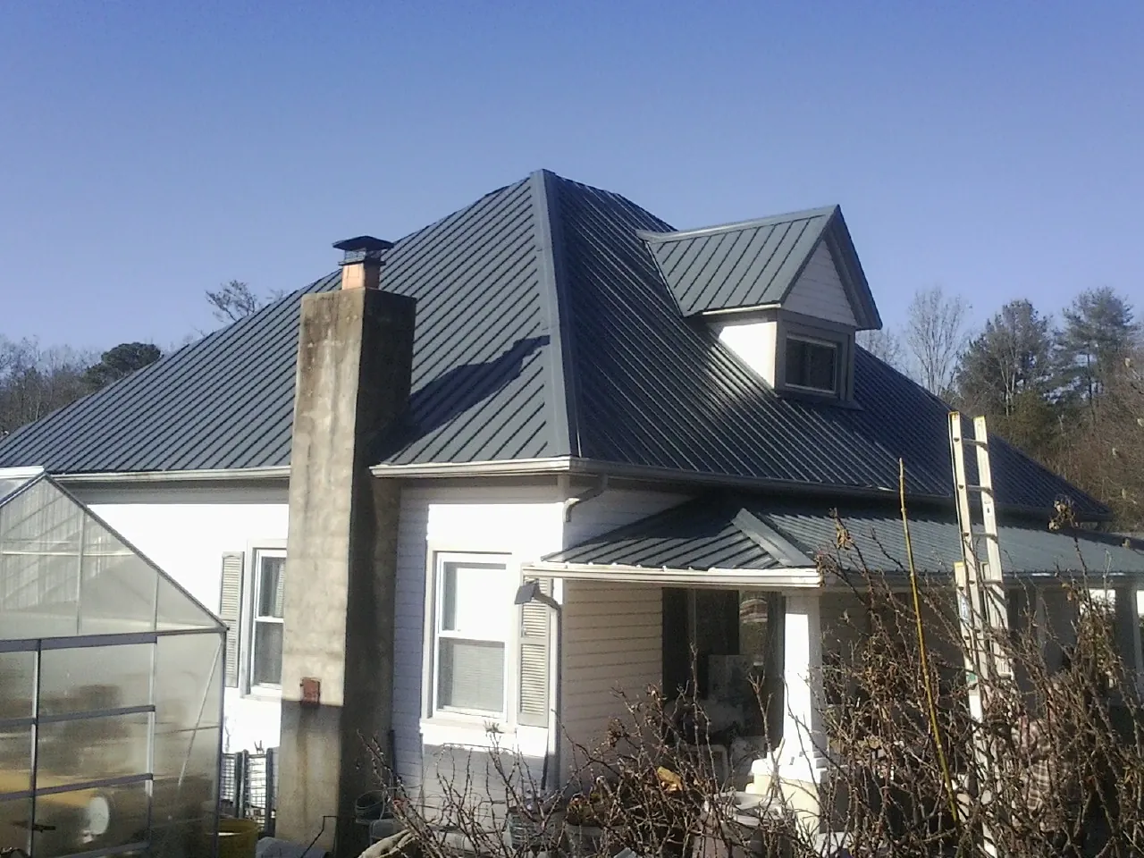 Dark blue standing seam metal roof on a white farmhouse with dormer — Slate & Tile Roof Repair by Roofing Brothers in Agawam