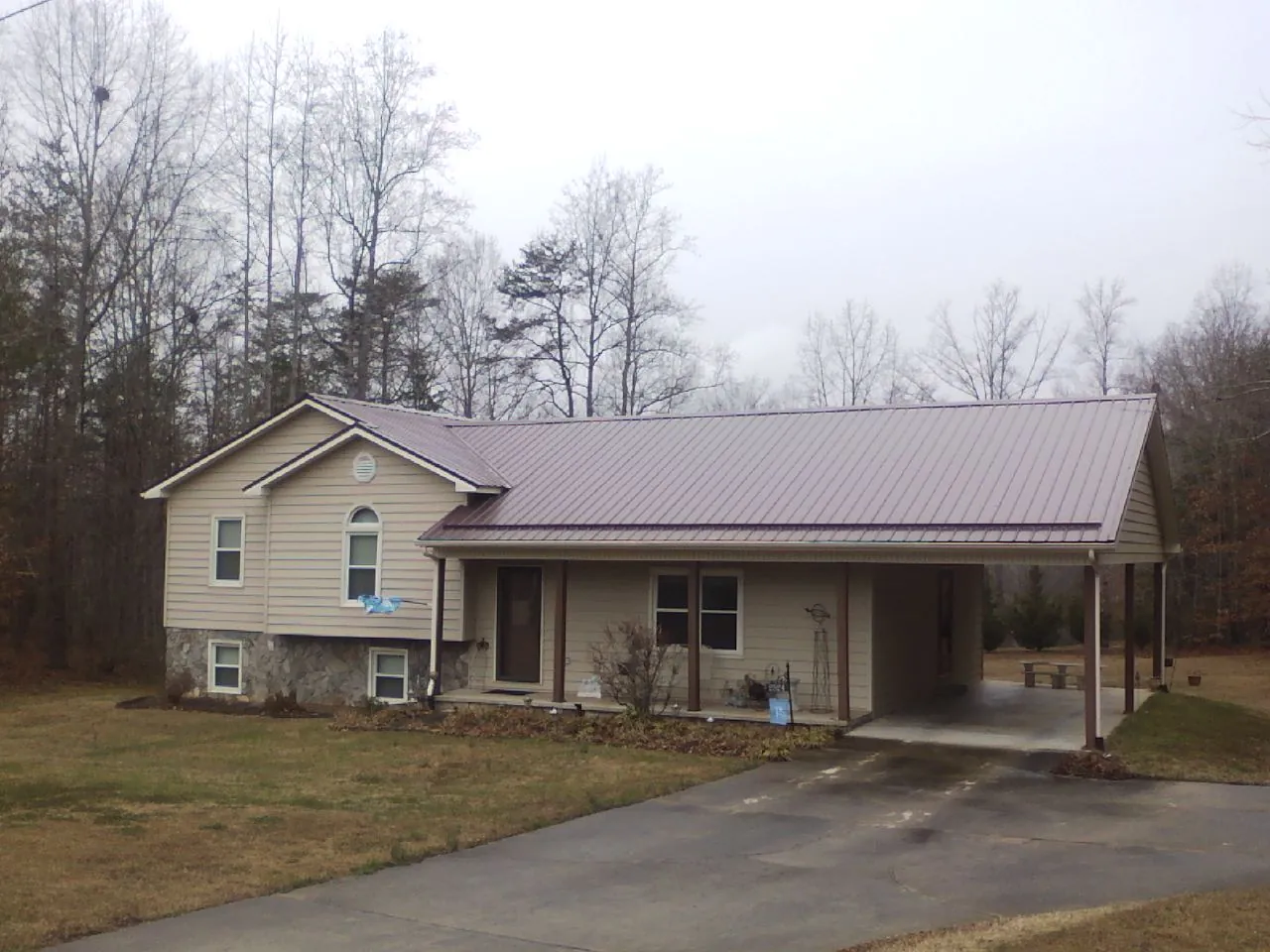 Burgundy metal roof on a tan split level home with an attached carport in Agawam