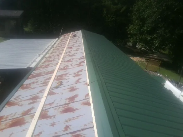 Old rusted panels beside newly installed green metal roofing — Wind Damage Roof Repair by Roofing Brothers in Agawam