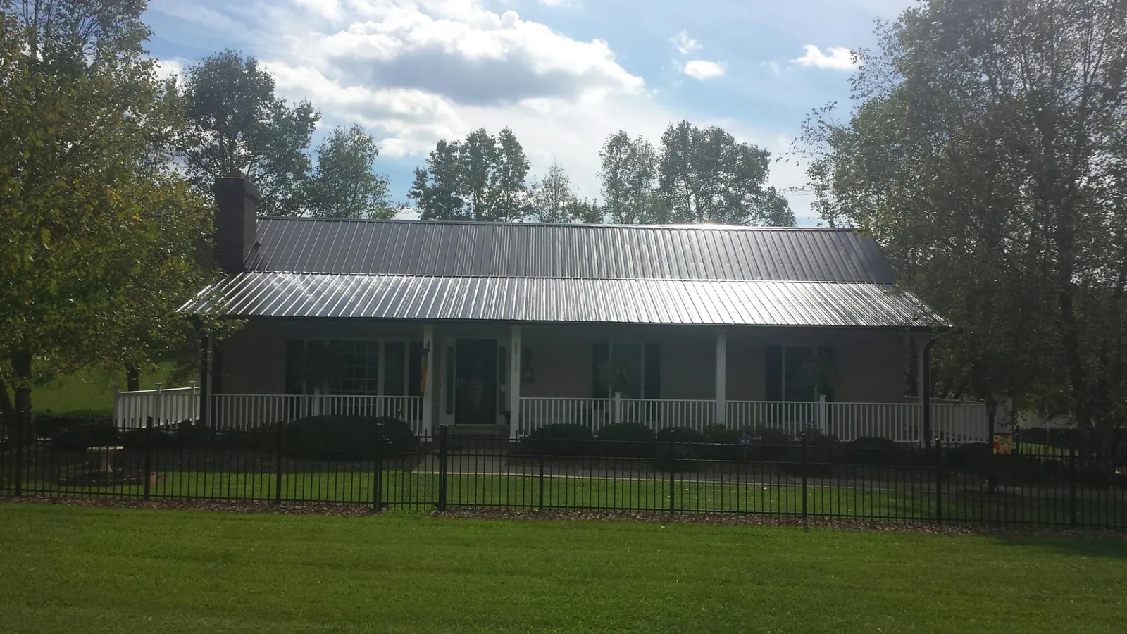 Gray metal roof on a brick ranch with a full width front porch — Gutter Guard Installation work by our crew in Agawam