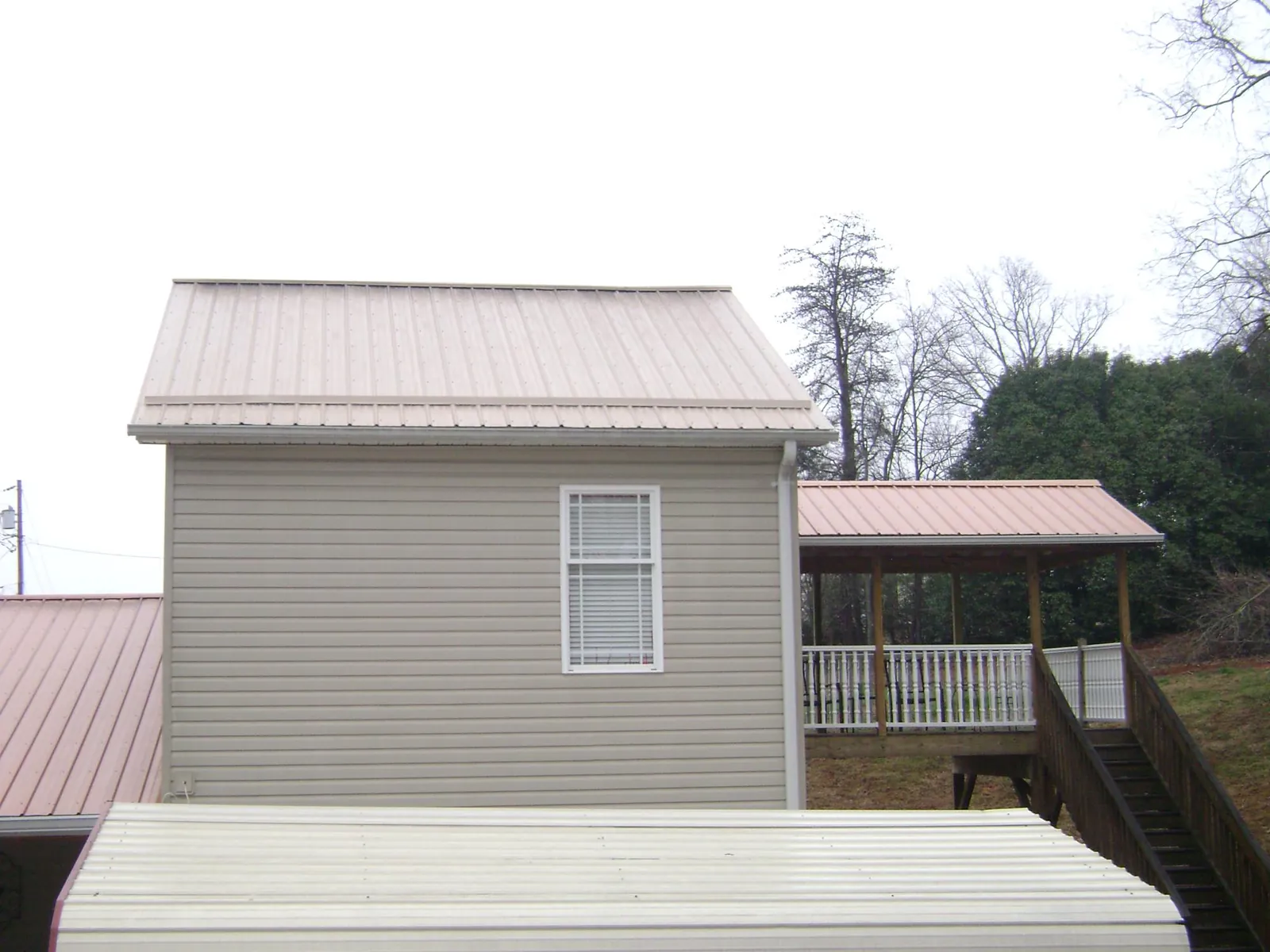 Tan metal roofs on a two story addition and attached porch, from a Roof Replacement job in Agawam