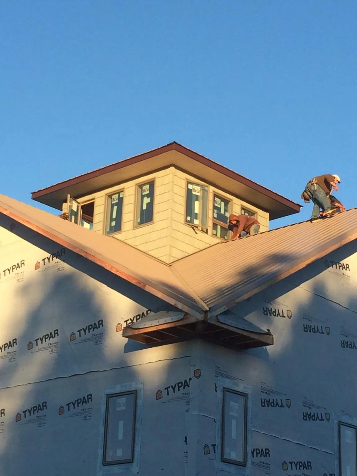 Roofers working around a rooftop cupola on a new metal roof at sunset — Roof Waterproofing in Agawam by Roofing Brothers